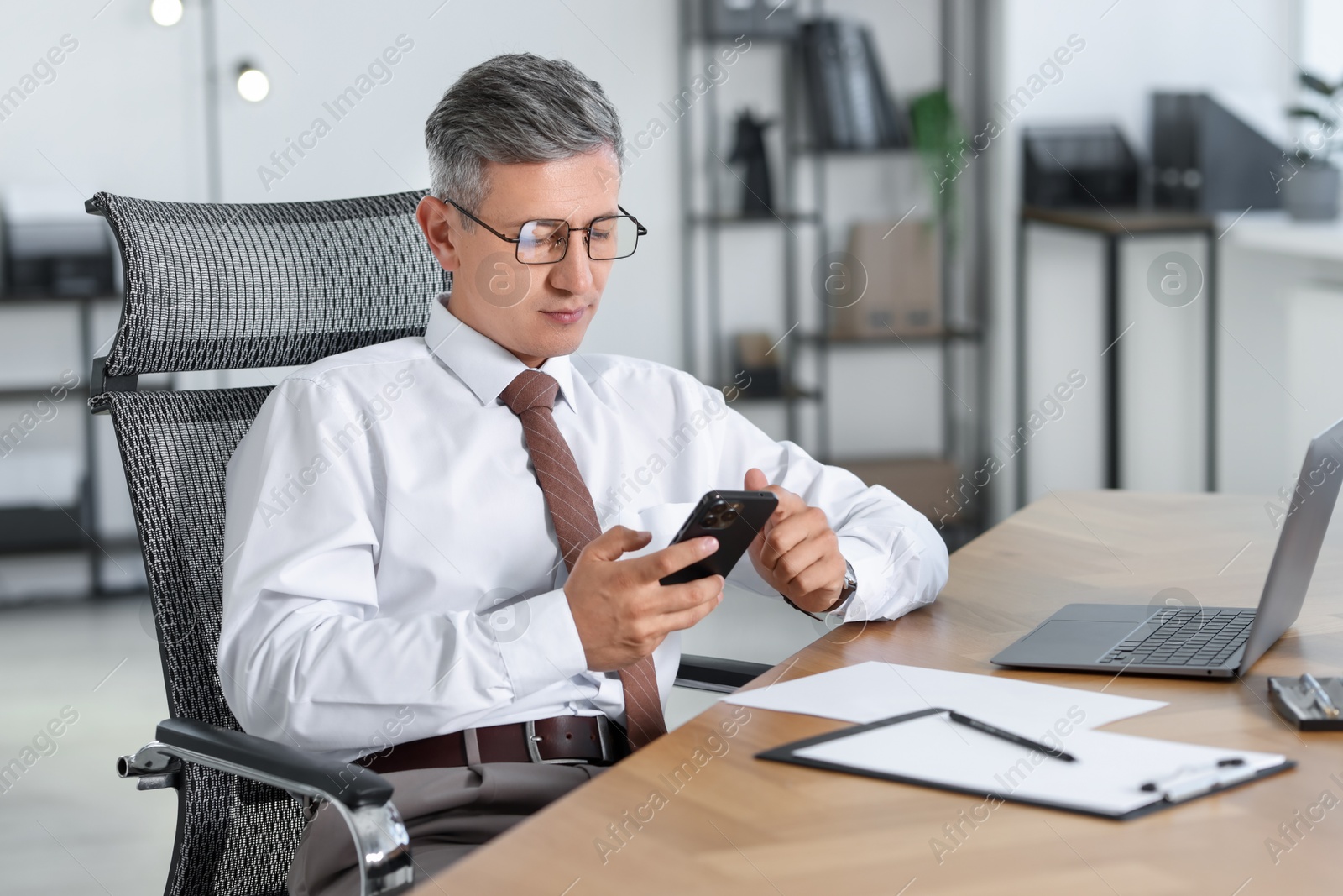 Photo of Businessman using smartphone at table in office