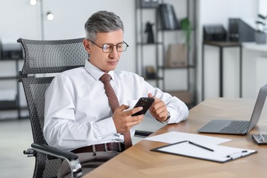 Businessman using smartphone at table in office