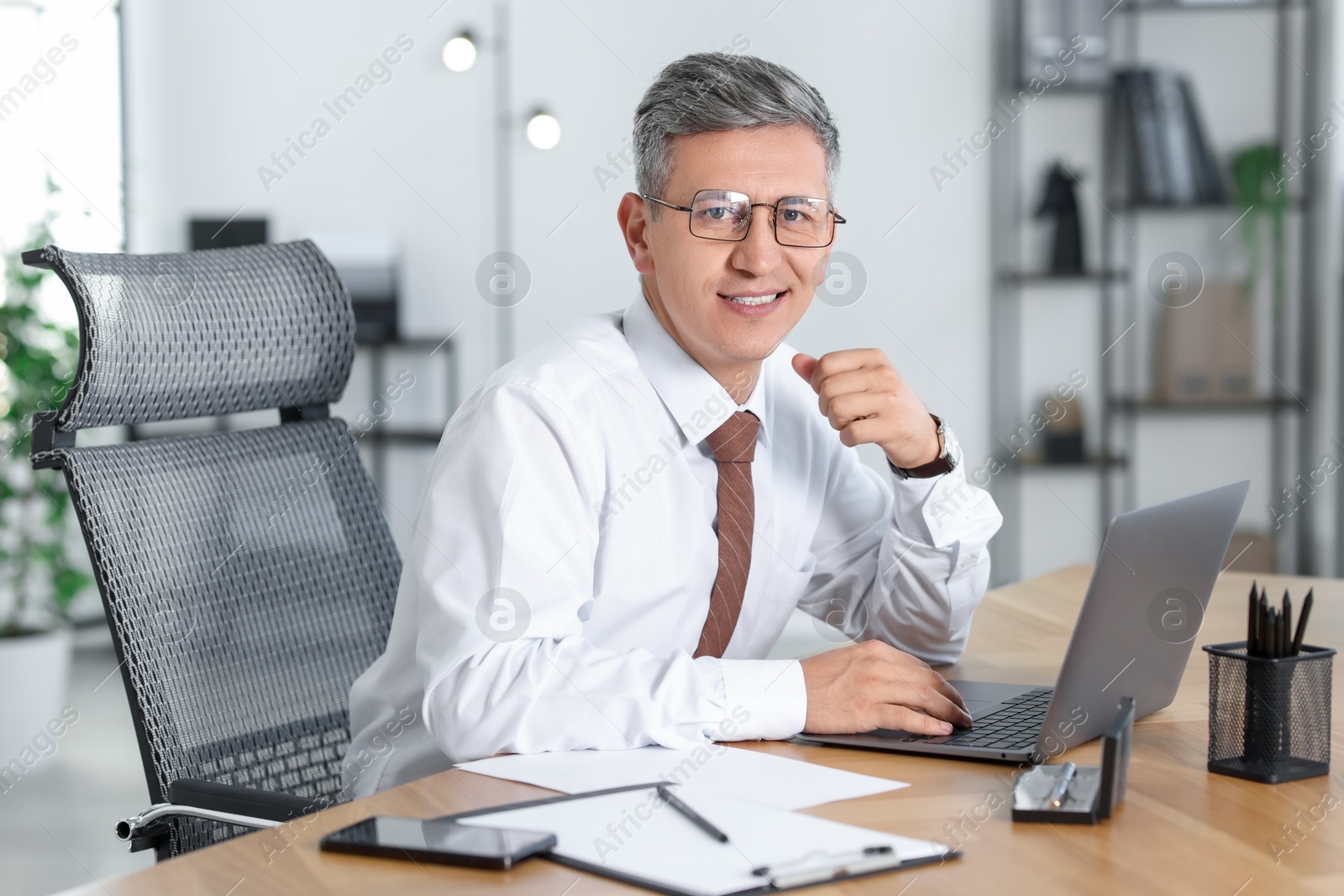 Photo of Businessman working on laptop at table in office