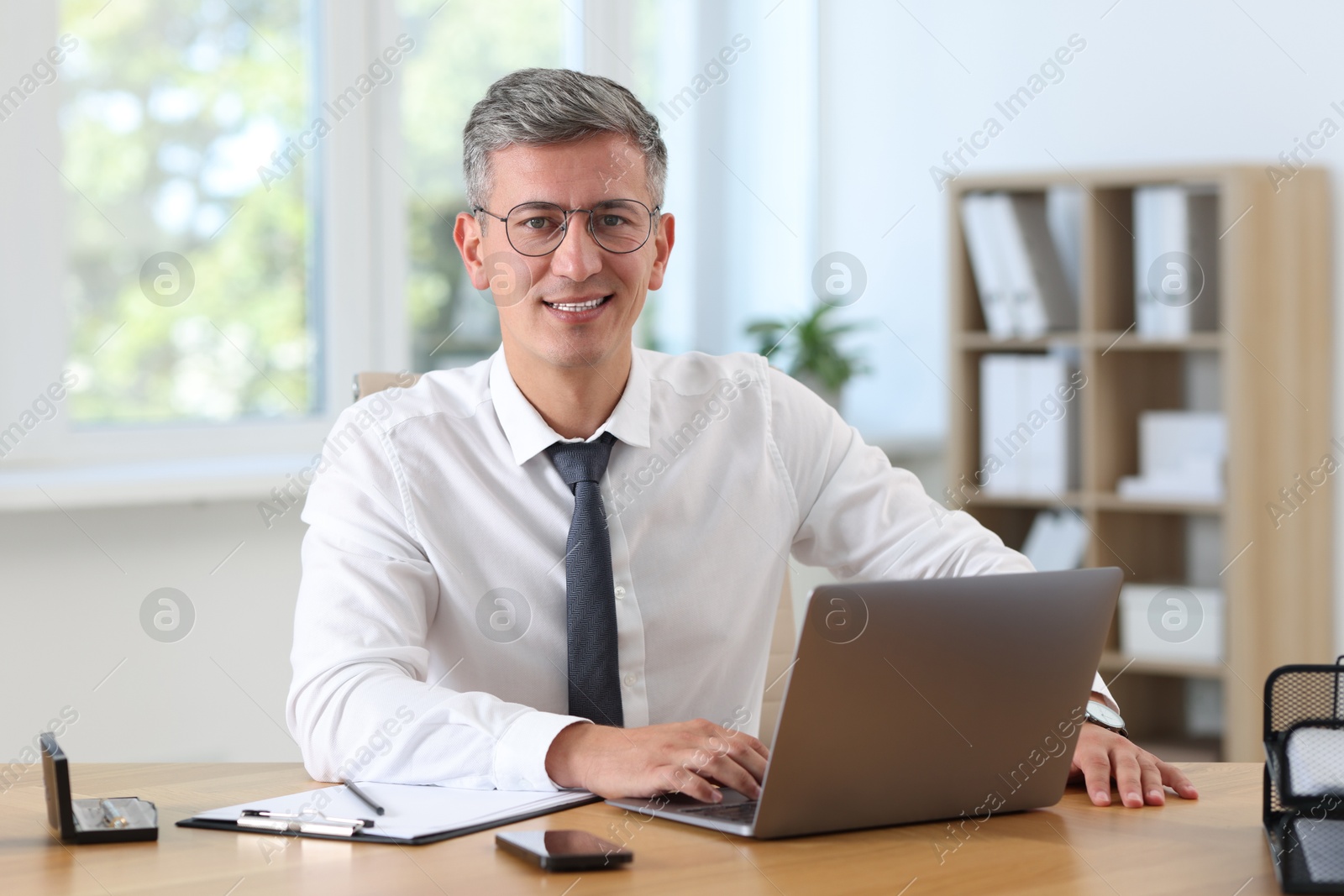 Photo of Businessman working on laptop at table in office