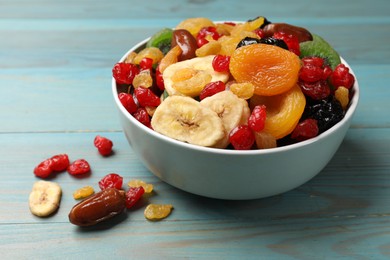 Photo of Mix of different dried fruits in bowl on light blue wooden table, closeup