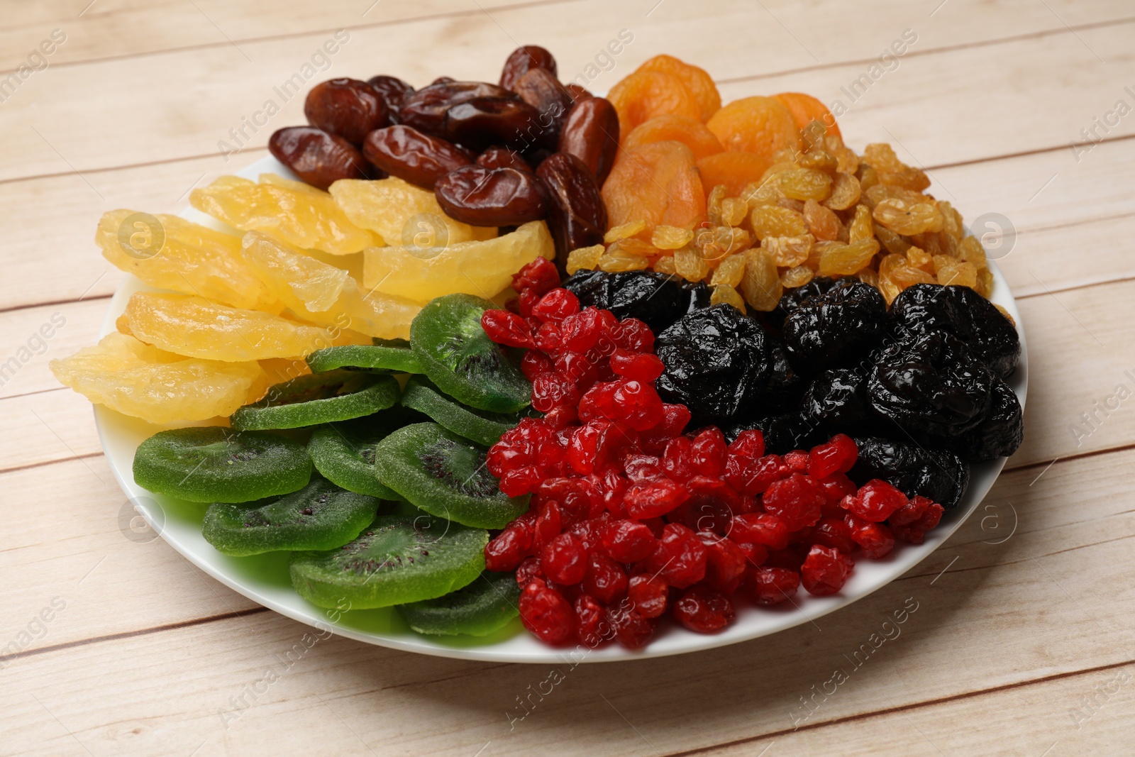 Photo of Mix of different dried fruits on wooden table, closeup