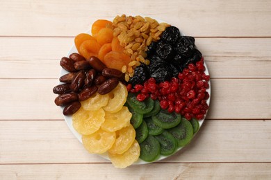 Photo of Mix of different dried fruits on wooden table, top view