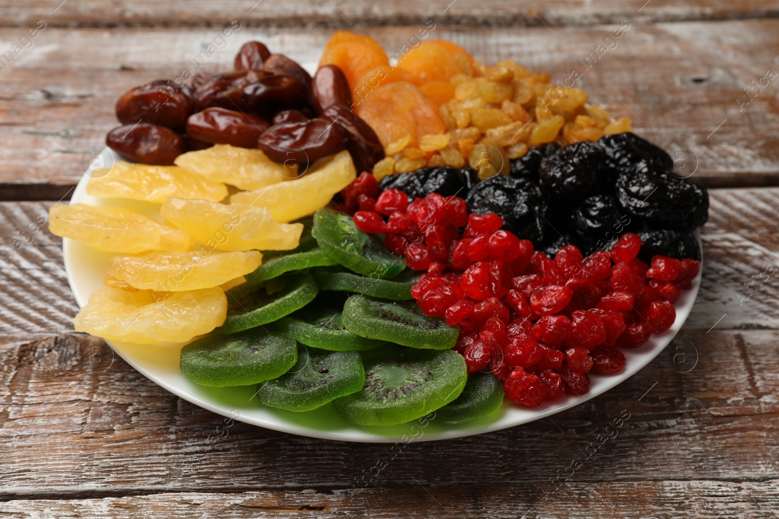 Photo of Mix of different dried fruits on wooden table, closeup