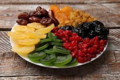 Photo of Mix of different dried fruits on wooden table, closeup