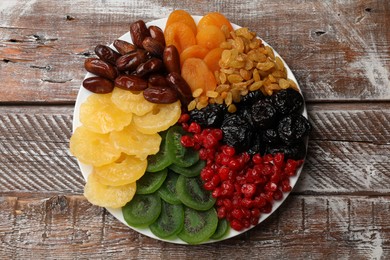 Photo of Mix of different dried fruits on wooden table, top view