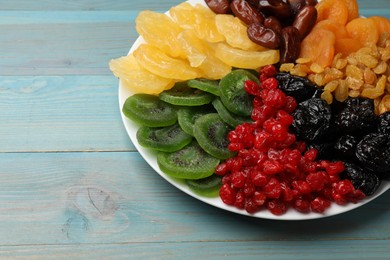 Photo of Mix of different dried fruits on light blue wooden table, closeup. Space for text