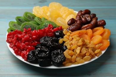 Photo of Mix of different dried fruits on light blue wooden table, closeup