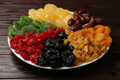 Photo of Mix of different dried fruits on wooden table, closeup