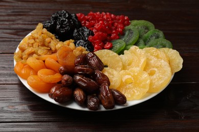 Photo of Mix of different dried fruits on wooden table, closeup