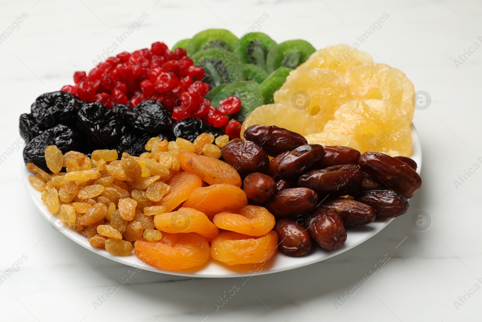 Photo of Mix of different dried fruits on white marble table, closeup