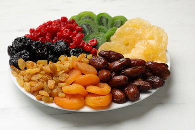 Photo of Mix of different dried fruits on white marble table, closeup