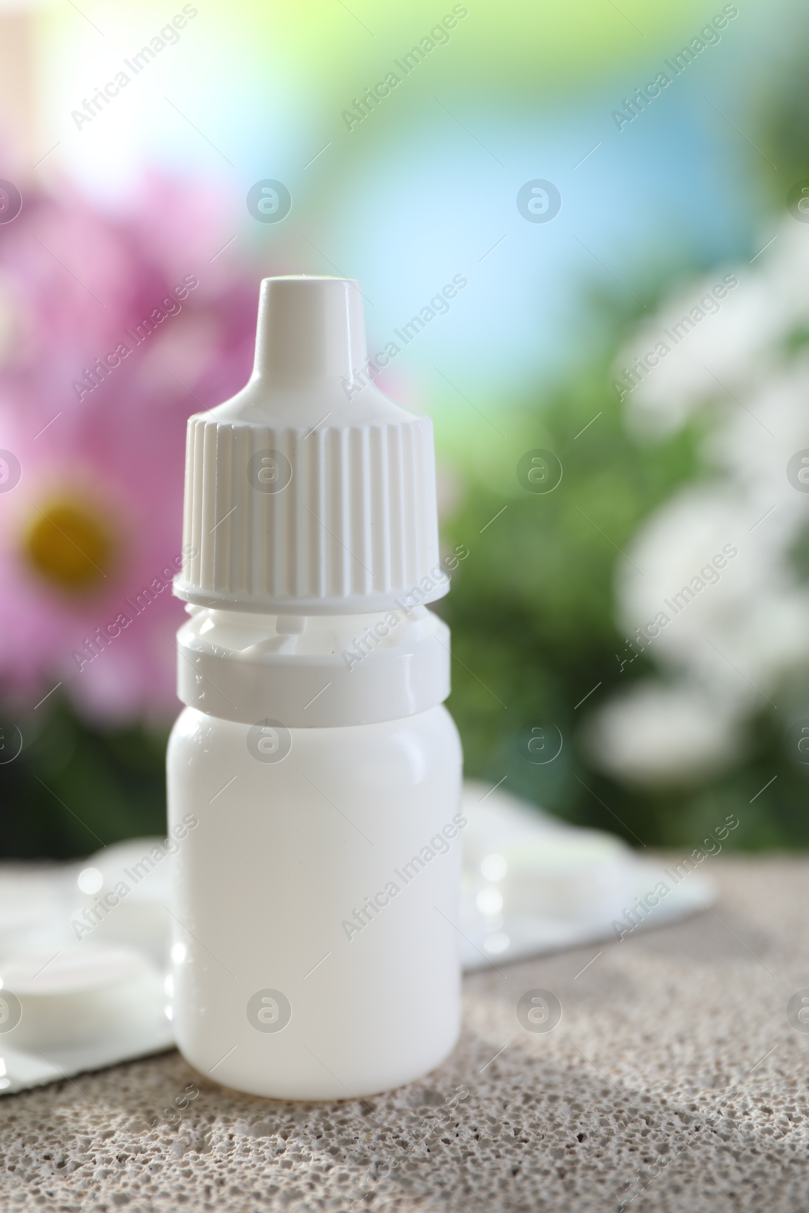 Photo of Allergy treatment. Bottle of medical drops and pills on stone against blurred background, closeup