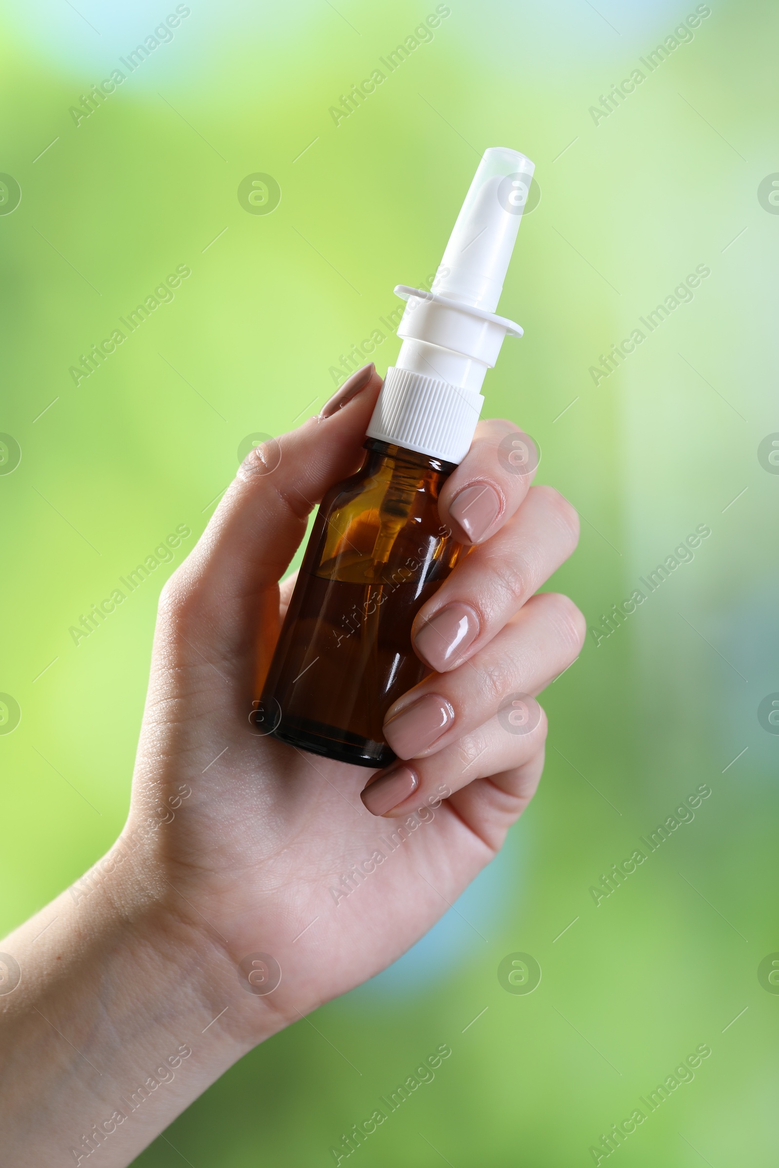 Photo of Allergy treatment. Woman with nasal spray on blurred background, closeup