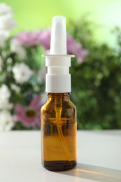 Photo of Allergy treatment. Nasal spray on white table against blurred background