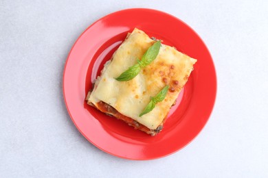 Photo of Piece of delicious cooked lasagna with basil on light table, top view