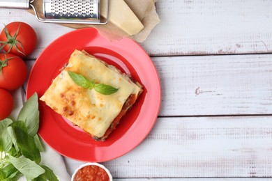 Photo of Delicious cooked lasagna with basil served on light wooden table, flat lay. Space for text