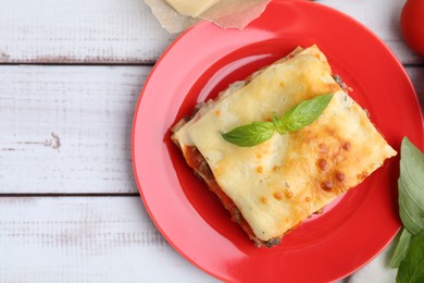 Photo of Delicious cooked lasagna with basil served on light wooden table, top view. Space for text