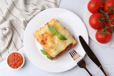 Delicious cooked lasagna with basil served on white textured table, flat lay