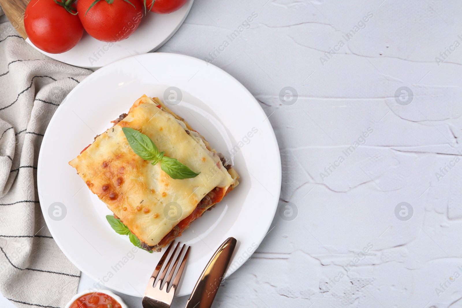 Photo of Delicious cooked lasagna with basil served on white textured table, top view. Space for text