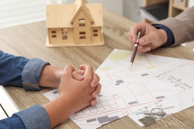 Photo of Real estate agent working with client at wooden table, closeup