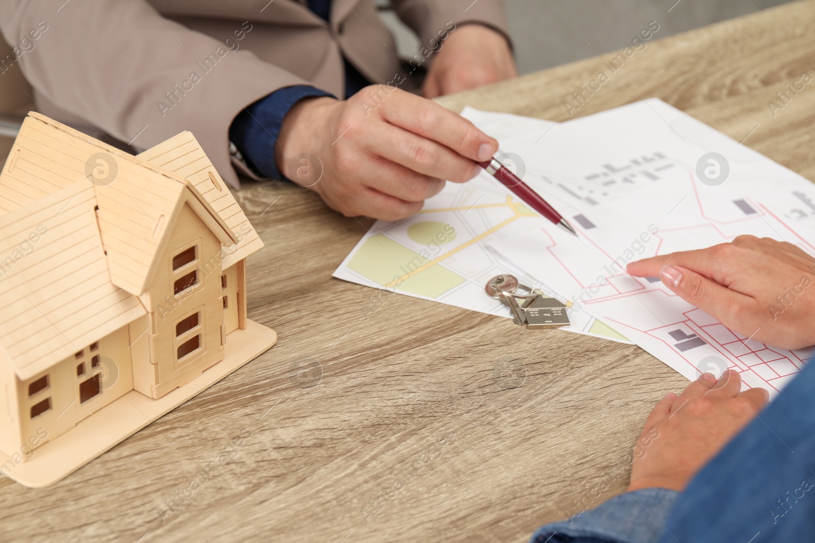 Photo of Real estate agent working with client at wooden table, closeup