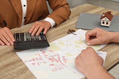 Photo of Real estate agent working with client at wooden table, closeup