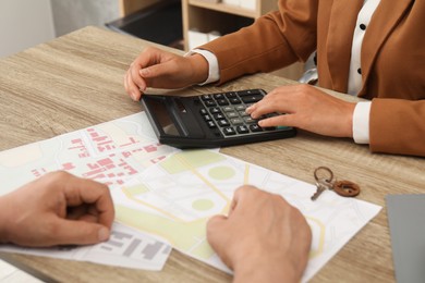 Photo of Real estate agent working with client at wooden table, closeup