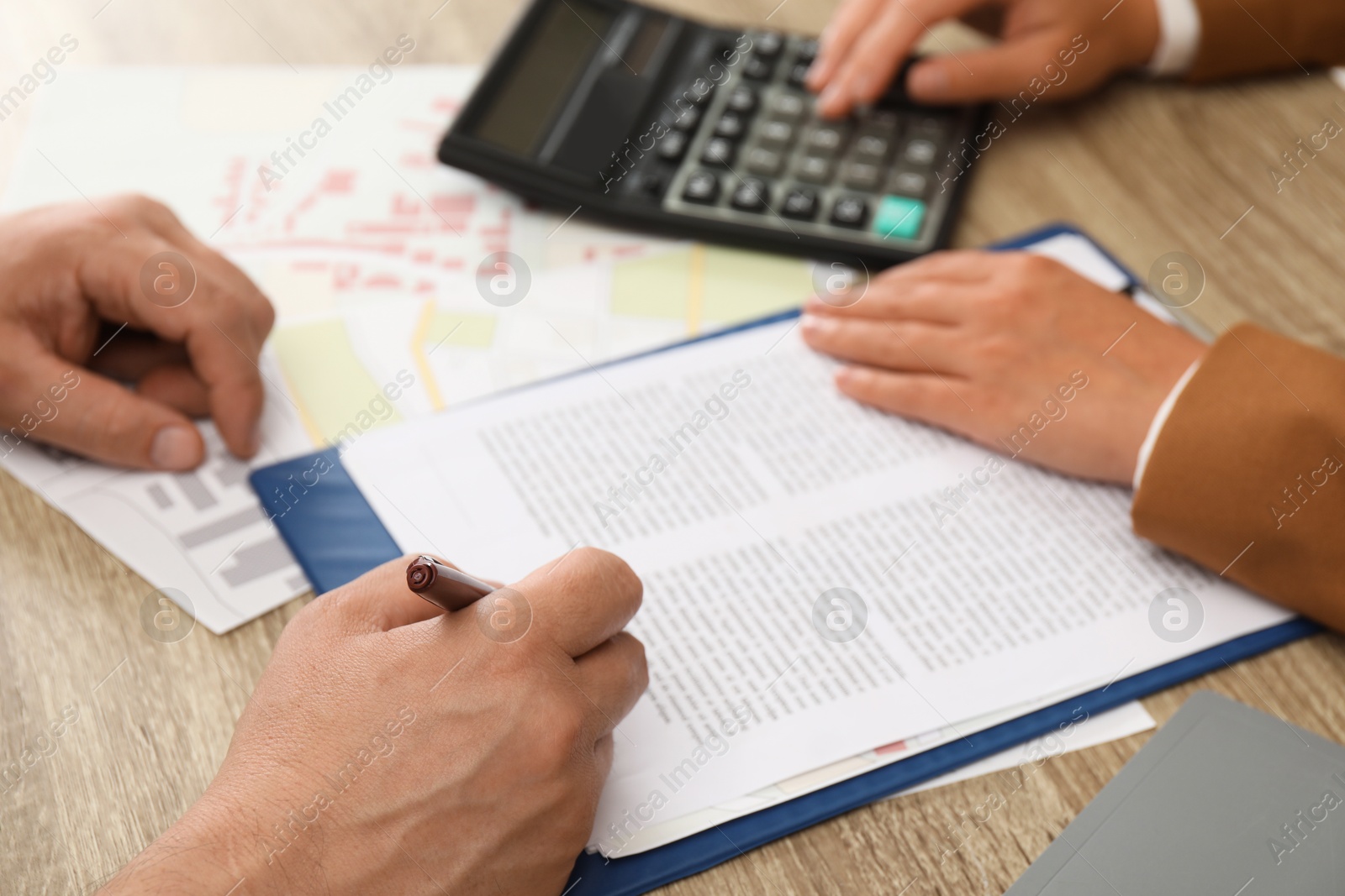 Photo of Real estate agent working with client at wooden table, closeup