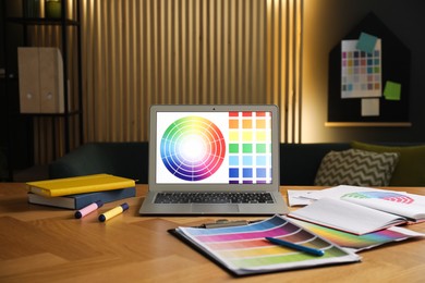 Photo of Designer's workplace with laptop, stationery and palettes on wooden table indoors