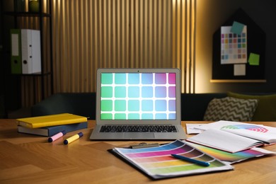 Photo of Designer's workplace with laptop, stationery and palettes on wooden table indoors