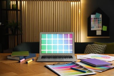 Photo of Designer's workplace with laptop, stationery and palettes on wooden table indoors