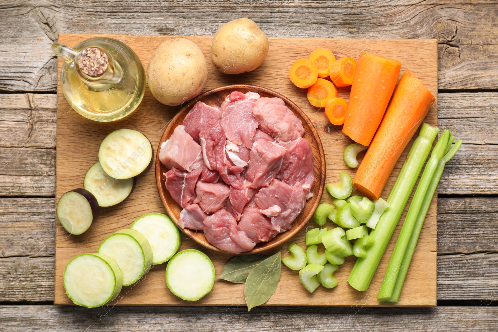 Photo of Cooking stew. Uncooked meat and vegetables on wooden table, top view