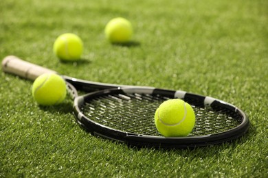 Tennis racket and balls on green artificial grass, closeup