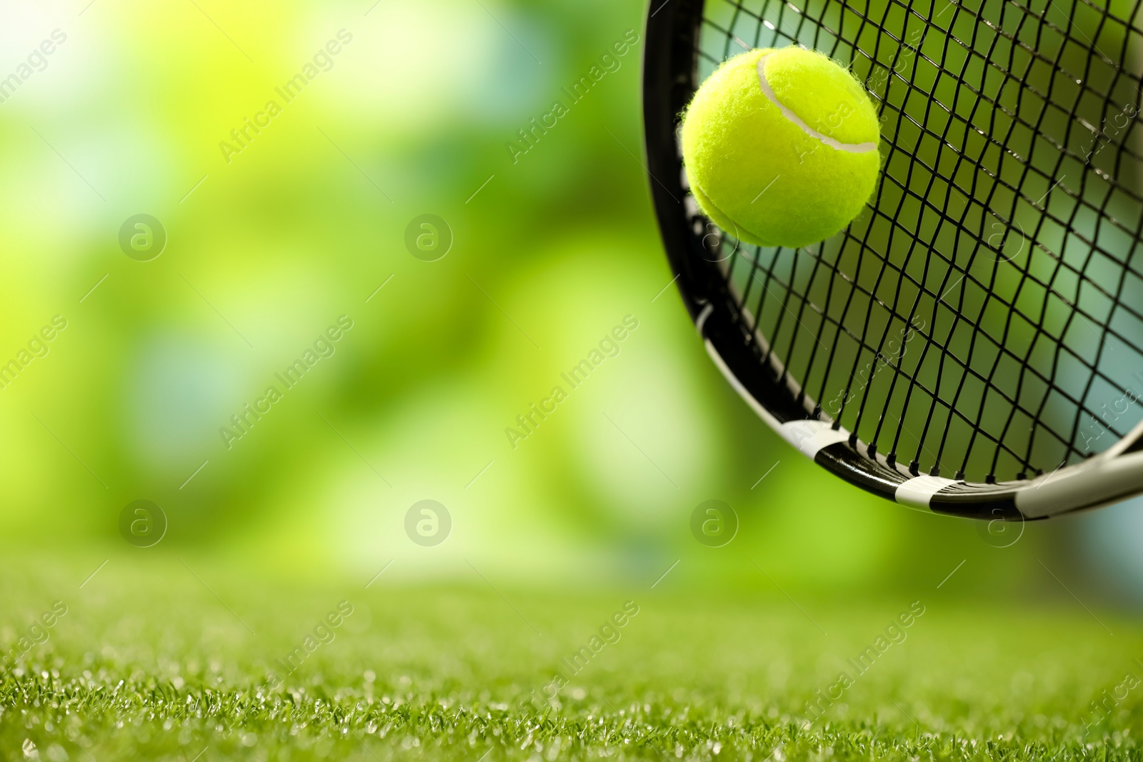 Photo of Tennis racket with ball on green artificial grass, closeup. Space for text