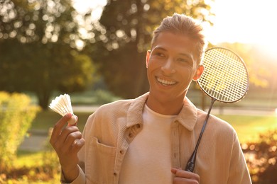 Photo of Happy young man with badminton racket and shuttlecock in park on sunny day