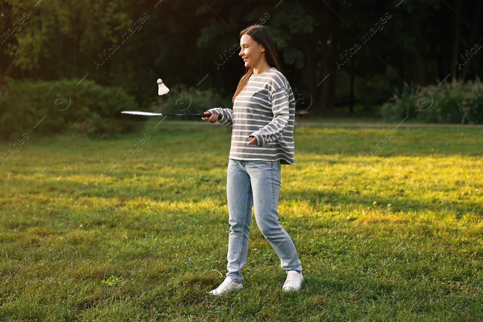 Photo of Young woman playing badminton racket in park