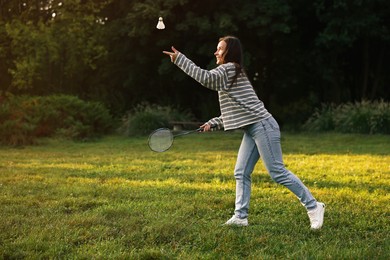 Photo of Young woman playing badminton racket in park