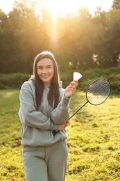 Photo of Happy young woman with badminton racket and shuttlecock in park on sunny day