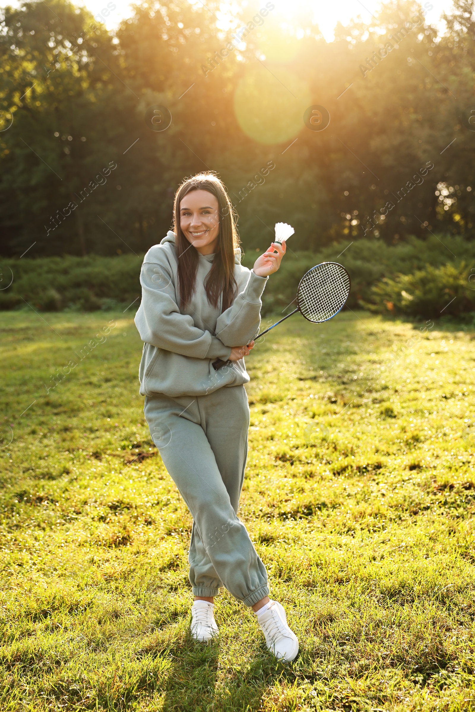 Photo of Happy young woman with badminton racket and shuttlecock in park on sunny day