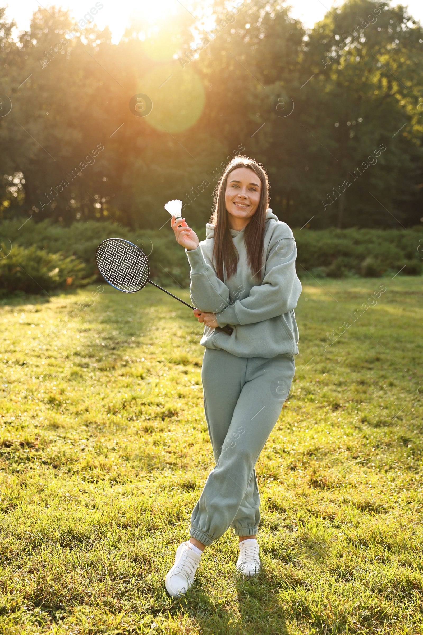 Photo of Happy young woman with badminton racket and shuttlecock in park on sunny day