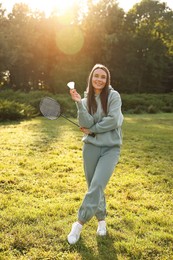 Photo of Happy young woman with badminton racket and shuttlecock in park on sunny day