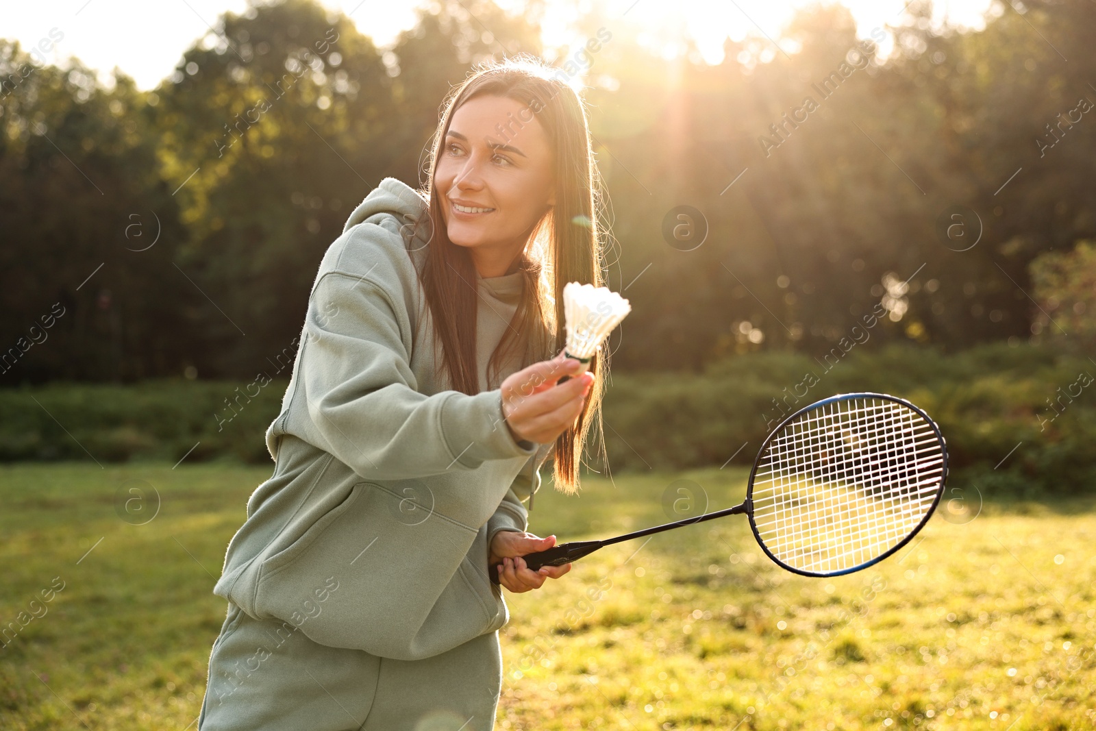 Photo of Happy young woman playing badminton racket in park on sunny day