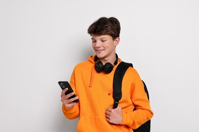 Photo of Teenage boy with headphones, smartphone and backpack on white background