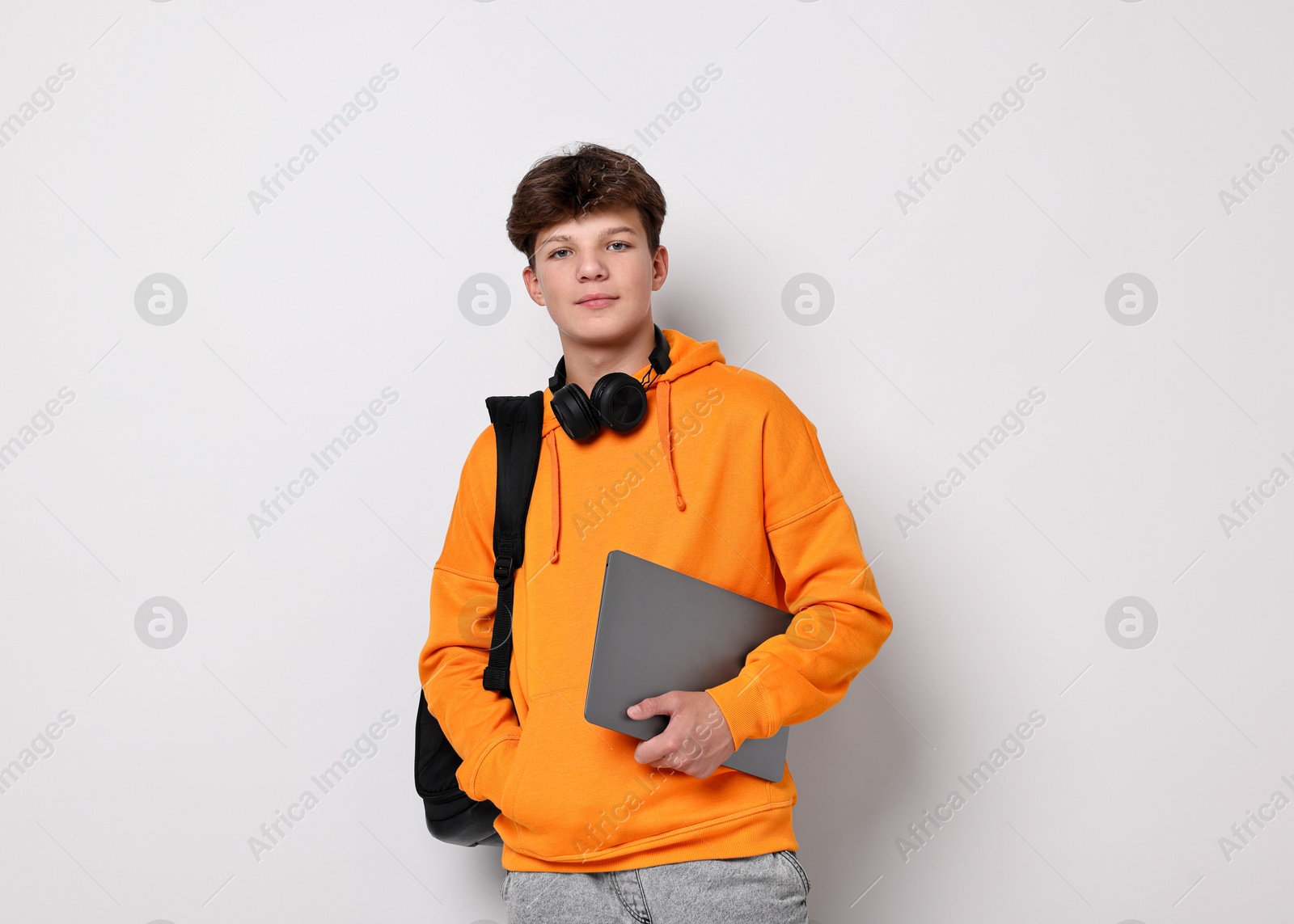 Photo of Teenage boy with headphones, laptop and backpack on white background