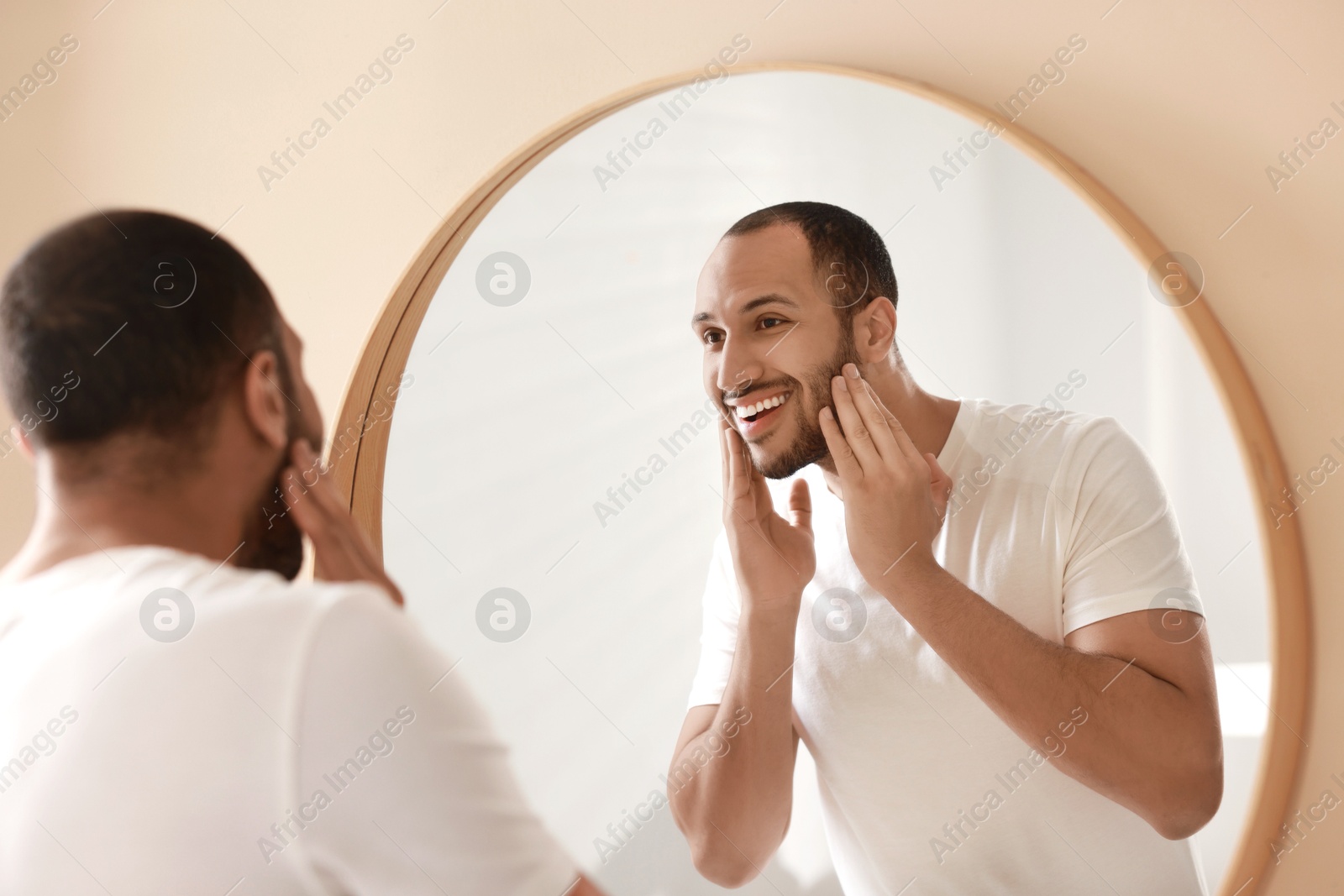 Photo of Smiling man looking at mirror in bathroom