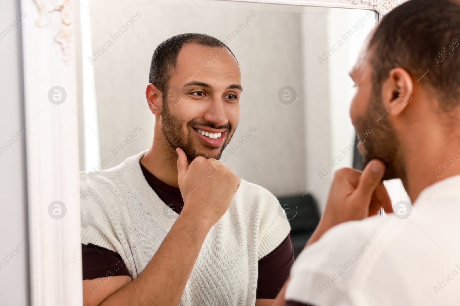 Photo of Smiling man looking at mirror at home