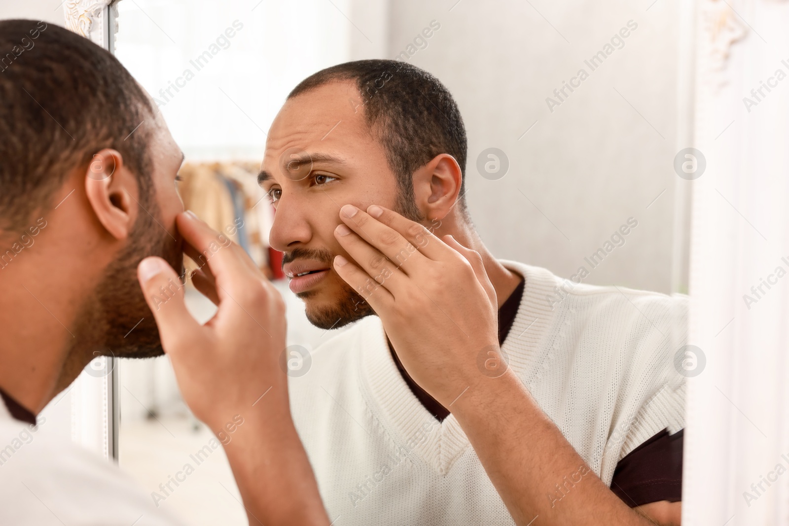 Photo of Worried man looking at mirror at home