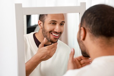 Smiling man looking at mirror at home