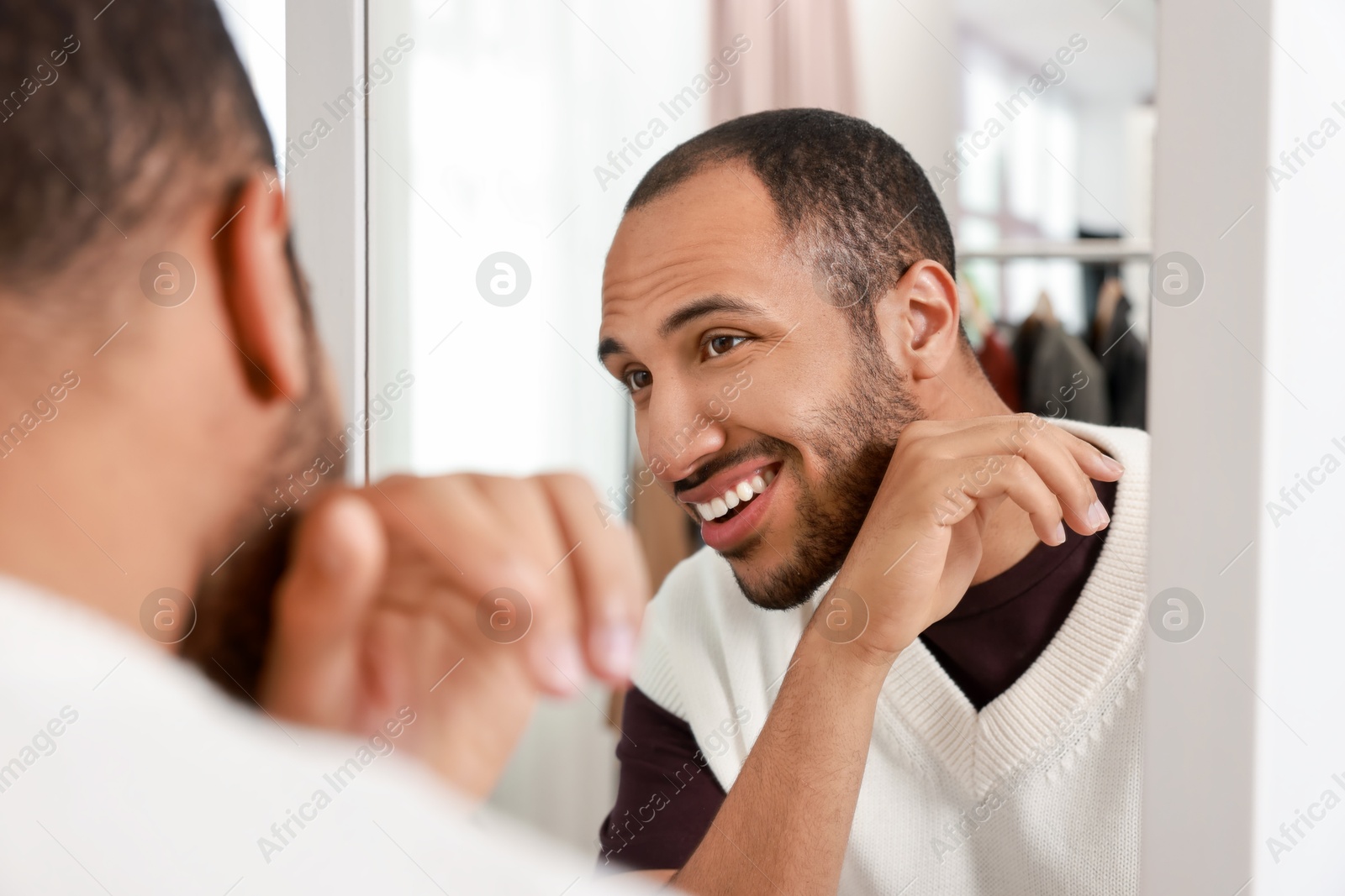 Photo of Smiling man looking at mirror at home